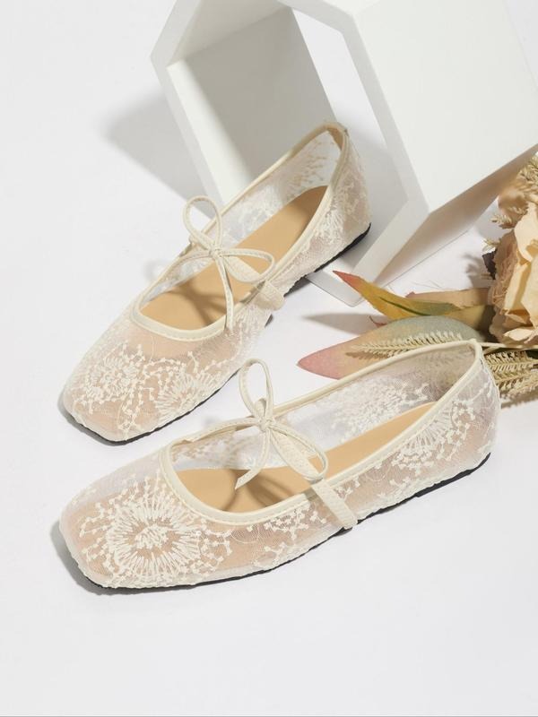 Pair of beige lace shoes with ribbon ties on a white background