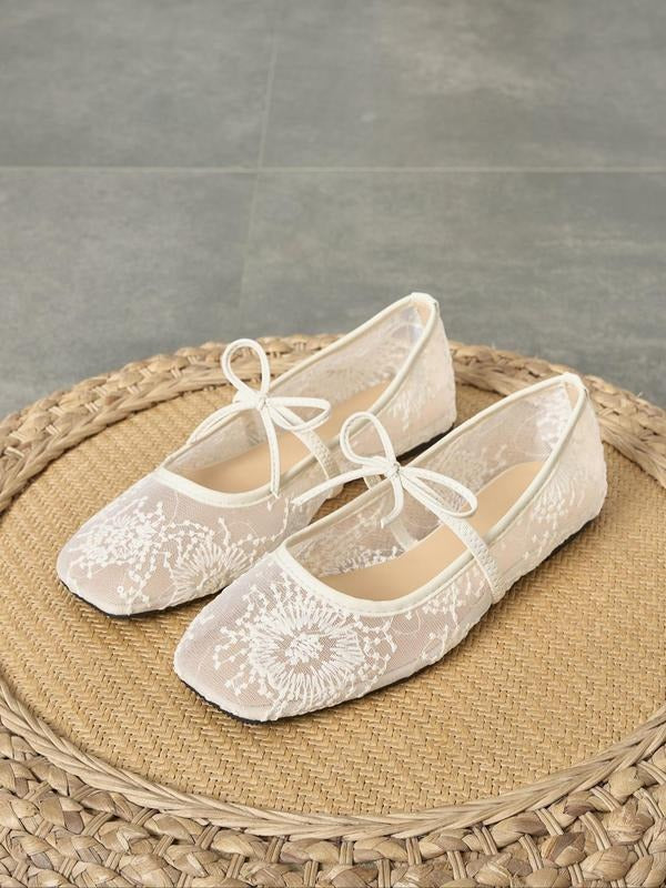 White lace shoes on a woven mat with a gray floor background
