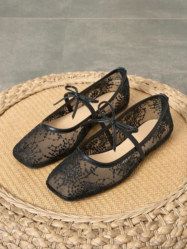 Black lace shoes with bows on a woven surface