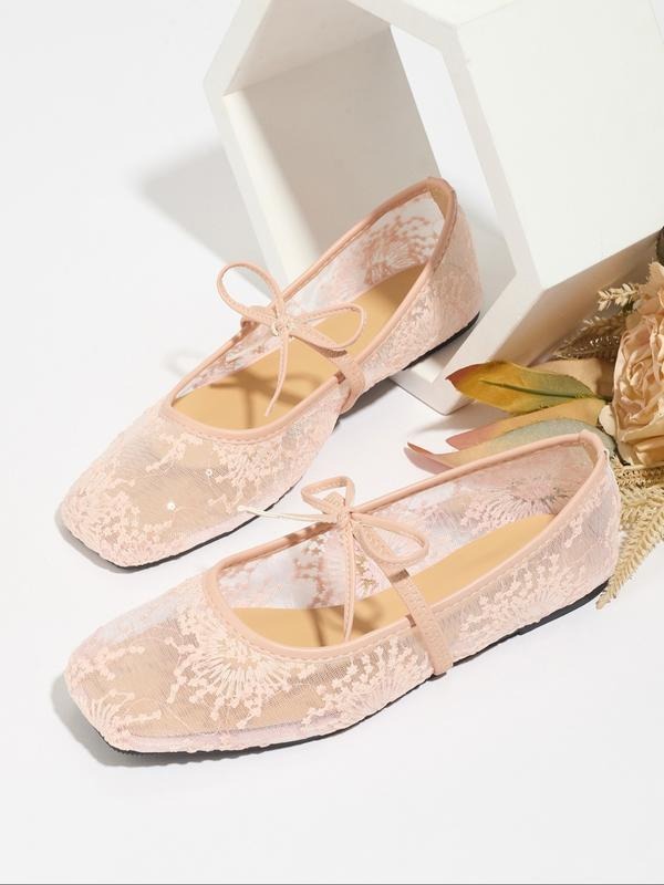 Pair of pink lace shoes with ribbons on a white background