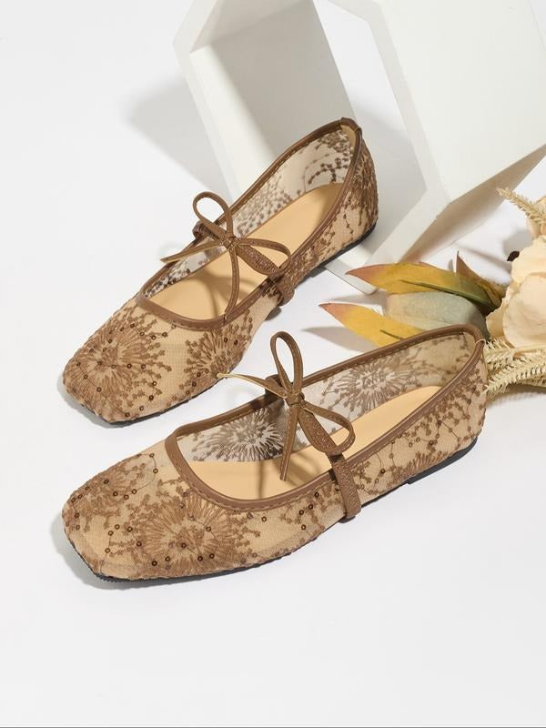 Pair of brown floral lace-up flats on a white background with decorative elements.