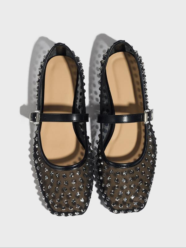Black studded flats on a light gray background