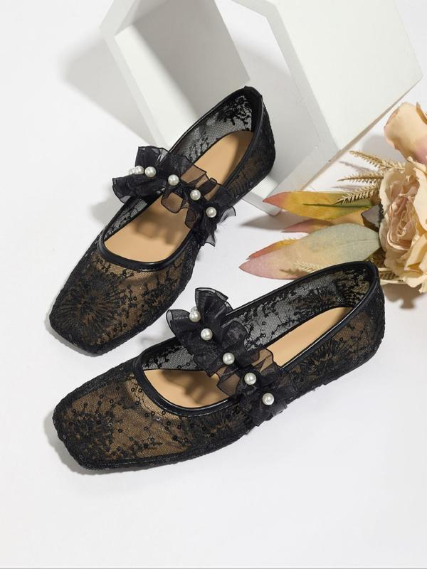 Black lace shoes with pearl details on a white background