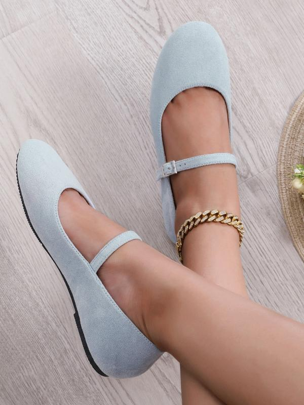Light blue flat shoes worn by a person on a light wooden floor.
