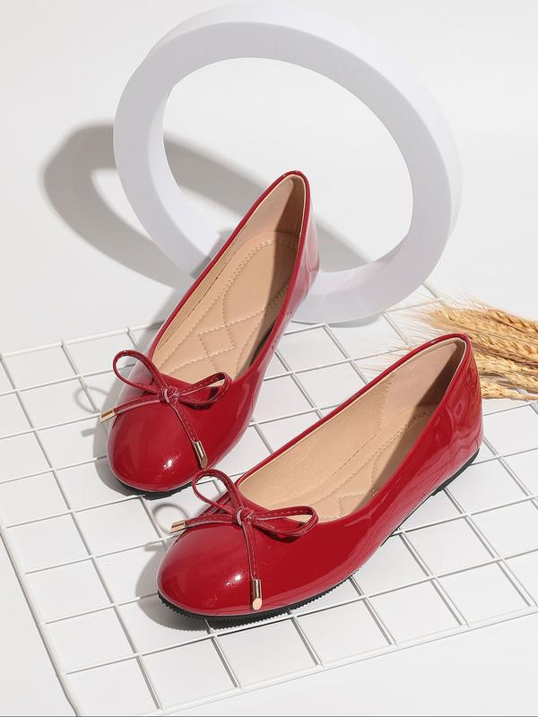 Red patent leather shoes with bow details on a white grid background