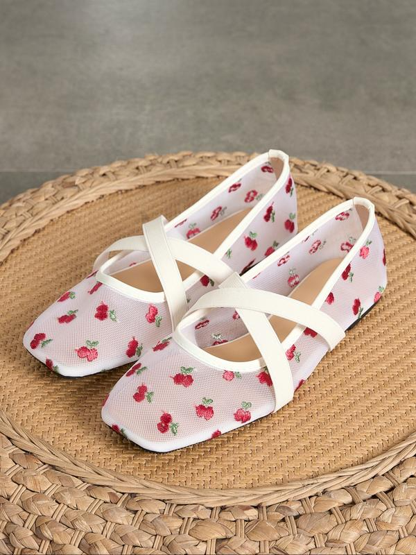Pair of white ballet flats with red floral pattern on a woven mat