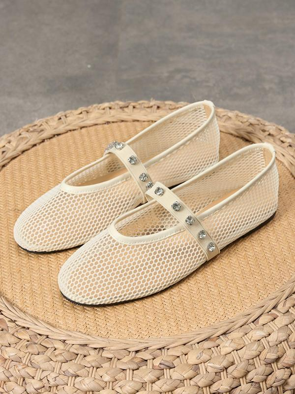 Pair of beige mesh shoes with rhinestone straps on a woven mat
