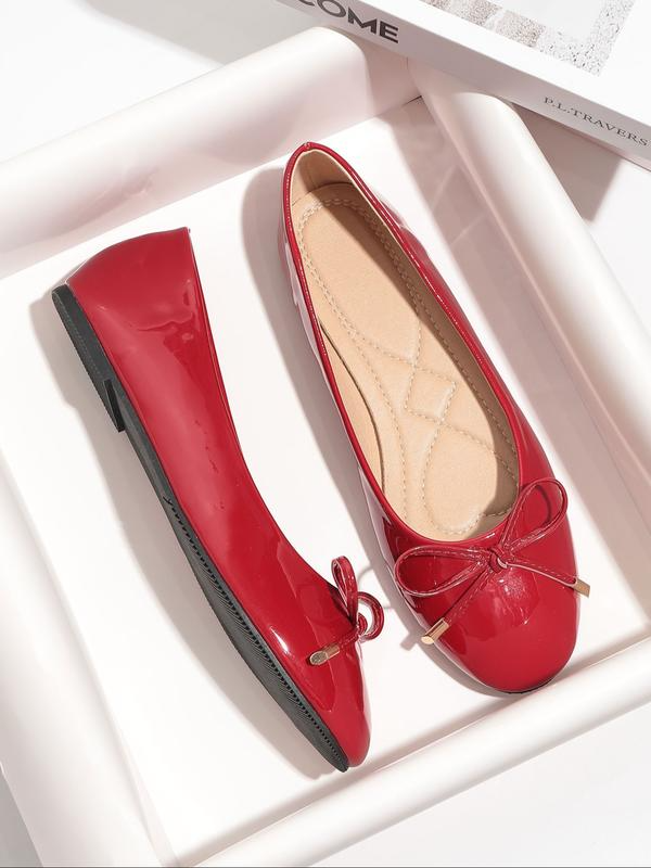 Red patent leather flat shoes with a bow on a white background