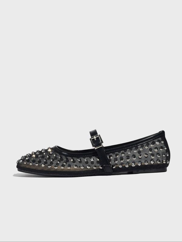Black studded flat shoe on a light gray background