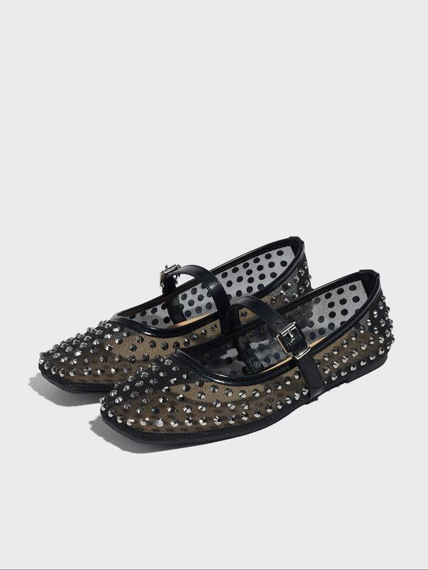 Black studded shoes on a light gray background